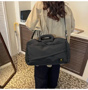 Detailed view of black travel duffel bag with shoulder strap, casual commuting style design.
