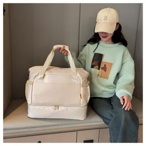 Detail view of a large beige travel duffel bag with double compartment indoor scene.