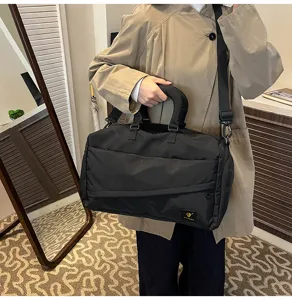 Black travel duffel bag detail, soft fabric, dual handles, adjustable shoulder strap for commute.