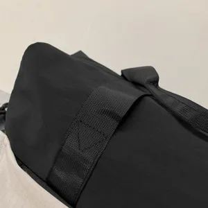 Black duffel travel bag detail showing durable nylon strap and strong stitching construction.
