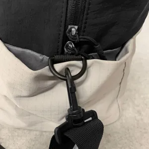 Close-up detail of travel bag hardware, durable zipper and metal D-ring hook for strap.