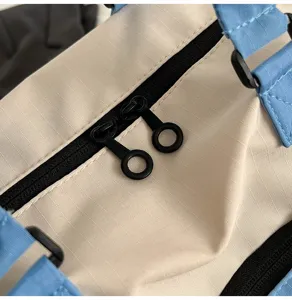 Close-up detail shot of color-block travel duffel bag zipper and soft fabric texture.