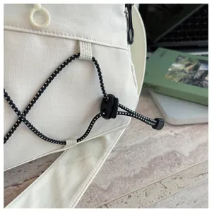 Close-up detail of white travel bag bungee cord and strap, minimalist outdoor design.