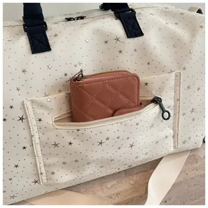 Close-up of travel duffel bag detail, off-white star pattern canvas with front pocket wallet
