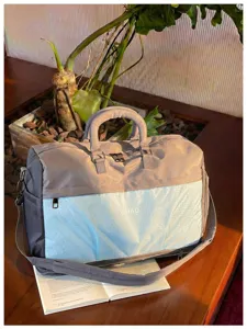 Large capacity travel duffel bag with grey and blue design, side pockets, and durable handles.