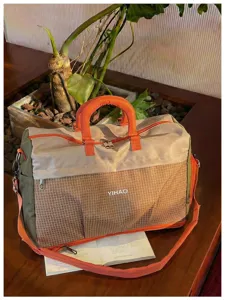 Large capacity travel duffel bag detail, orange handles and grid pattern design for fitness.