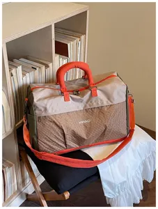 Detailed view of the large capacity travel duffel bag with grid pocket and orange handles.