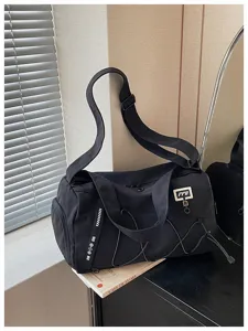 Close-up detail of the black travel duffel bag showing elastic cords, side pocket, and branding.