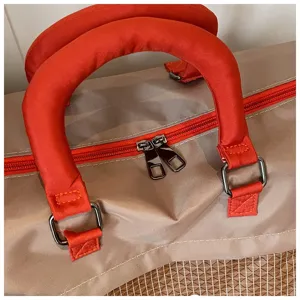 Close-up detail of travel duffel bag handle, bright orange zipper, and durable fabric.