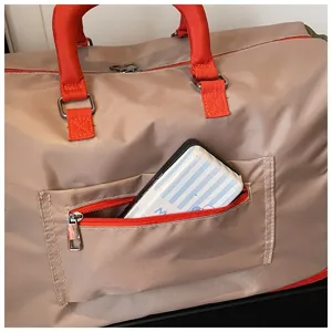 Travel duffel bag detail showing durable red handles and convenient front zipper pocket.