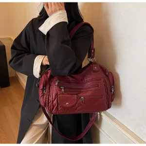 Vintage distressed red faux leather shoulder bag with multiple zippers and spacious design.