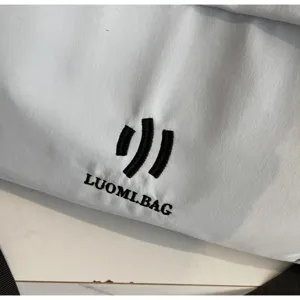 Close-up detail of travel bag fabric showing neat black embroidery logo and durable material.