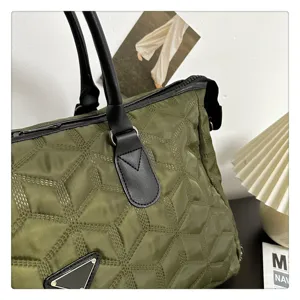 Sac de voyage matelassé vert avec poignées noires et détails de conception triangulaires.