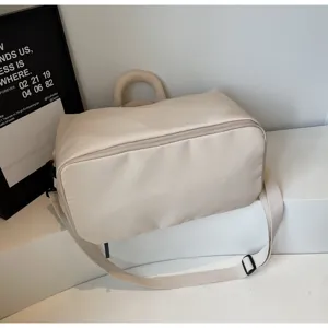 Sac de voyage fourre-tout beige minimaliste avec bandoulière réglable, léger et durable.