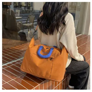 Detail shot of orange travel duffel bag, showing blue handles, side zipper, and daily commute scene.