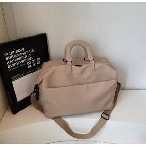 Minimalist travel duffel bag detail, beige fabric, adjustable shoulder strap, side pocket design.