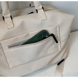 Vue détaillée de la poche zippée avant du sac de voyage en toile avec un téléphone.