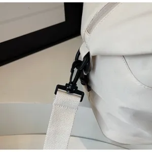 Gros plan sur la boucle de sangle du sac de voyage, toile durable et quincaillerie noire.