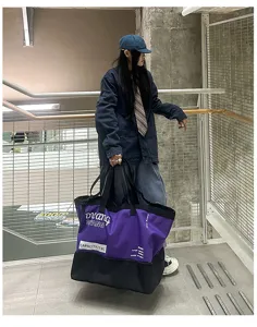 Détail d'un grand sac de voyage violet, montrant un tissu résistant et un design spacieux.
