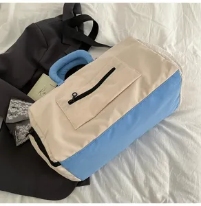 Detail view of the color-block travel duffel bag with front zipper pocket and carry handles.