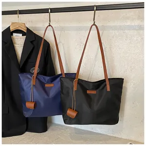 Κοντινή άποψη από casual νάιλον τσάντες tote σε κρεμάστρα με καφέ λουριά και μικρή θήκη.