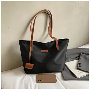 Λεπτομερής όψη μαύρης νάιλον τσάντας tote, casual τσάντα ώμου με καφέ δερμάτινα χερούλια.