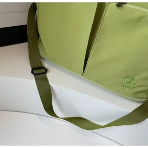 Detailed view of the light green travel shoulder bag showing durable green strap and embroidered logo design.