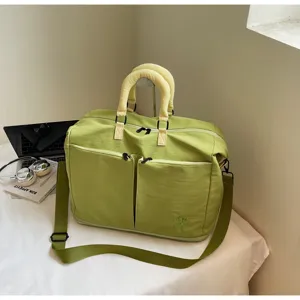Detailed view of the stylish green travel duffel bag, showing dual handles and front pockets.