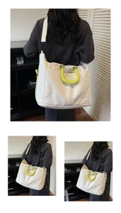 Canvas travel shoulder bag detail view, white body with vibrant green handles and strap.