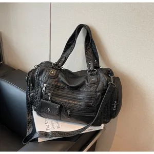 Detail view of a retro distressed black leather motorcycle shoulder bag with multi-zipper design.