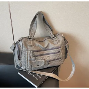 Grey vintage motorcycle bag detail with multiple zippers and distressed leather texture.