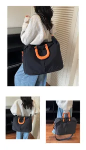 Detailed view of black travel duffel bag with vibrant orange handles, multi-functional design.