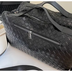 Primo piano dettagliato della borsa da viaggio in pelle intrecciata nera con tasca laterale.