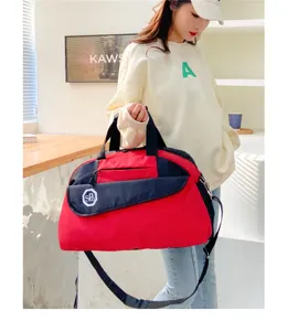 Detailed view of the red and black travel duffel bag showing durable zippers and dual handles.