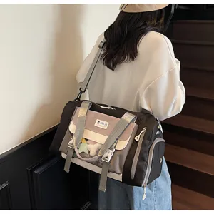 Detail view of colorblock travel duffel bag with clear window pocket and adjustable strap.