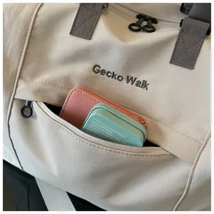 Close-up detail of a casual travel duffel bag showing textured fabric, front zipper pocket and handle.