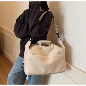 Vue détaillée du sac de voyage beige porté par un modèle, montrant une grande capacité.