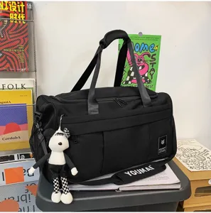 Black travel duffel bag with checkered bear pendant, large capacity weekend luggage bag.