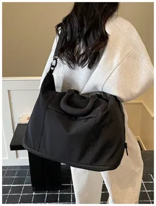 Stylish black travel duffel bag for women, lightweight nylon gym shoulder bag for commuter daily use.