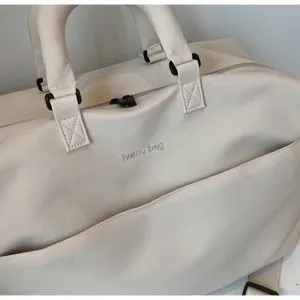 Close-up detail of beige canvas travel duffel bag with reinforced handles and secure zipper.