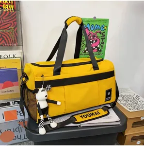 Yellow travel duffel bag with black straps and cute plush pendant for short trips.