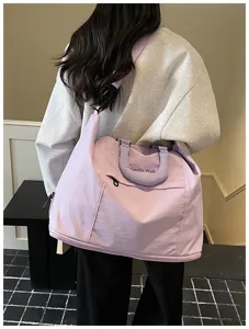 Detail shot of the light purple travel shoulder bag worn by a model in an indoor setting.