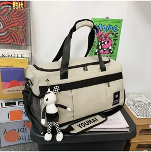 Multi-functional beige travel duffel bag with black straps and cute checkerboard doll pendant.