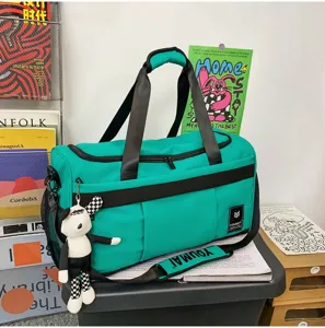 Detailed view of the turquoise travel duffel bag with black straps and cute pendant design.