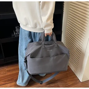 Vue détaillée du grand sac de voyage gris avec bandoulière réglable et poche frontale.