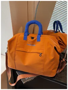 Orange travel duffle bag with blue handles, stylish cotton shoulder bag for gym and weekend trips.