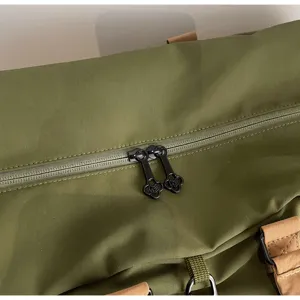 Grüne Reise-Duffelbag Detailansicht, wasserdichtes Gewebe mit braunem Lederbesatz und Metallbeschlägen.
