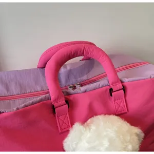 Vue détaillée d'un sac de voyage rose élégant, mettant en valeur la poignée et la fermeture éclair.