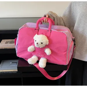 Vue rapprochée du sac de voyage rose avec un adorable ours en peluche et des poignées.