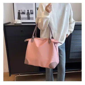 Large capacity pink travel duffel bag with brown leather handles, detail view in lifestyle scene.
